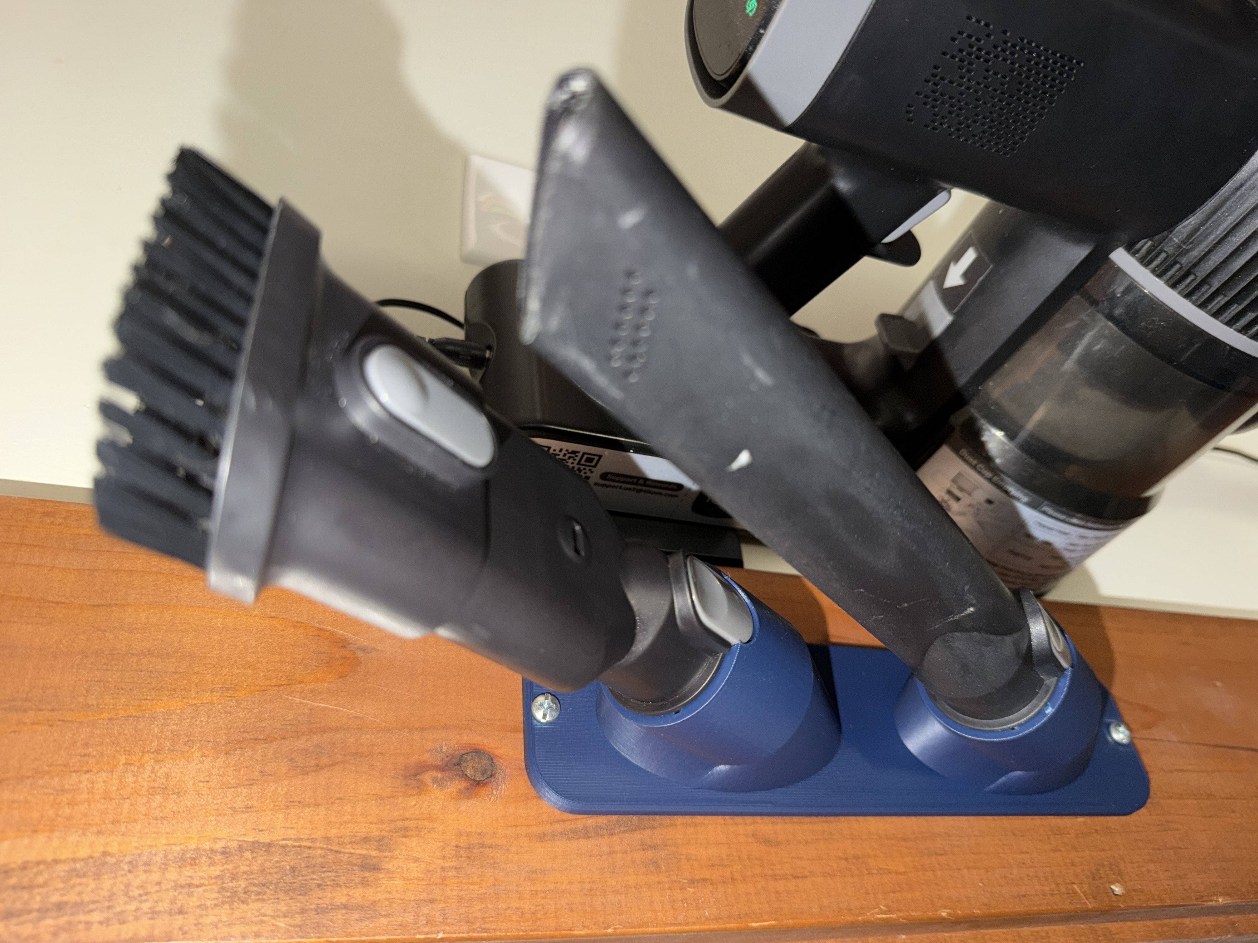 Completed blue dock fastened to a wooden surface, holding two vacuum accessories beside the vacuum.
